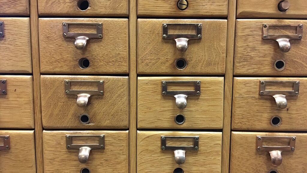 Rows of wooden library card catalog drawers with brass handles